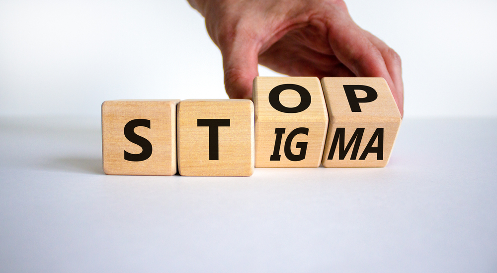 Person turns wooden cubes with words stop stigma